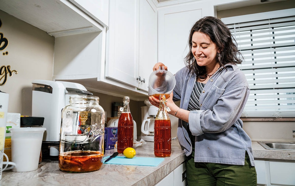 Image of Marin Warshay bottling Kombucha on a kitchen counter.