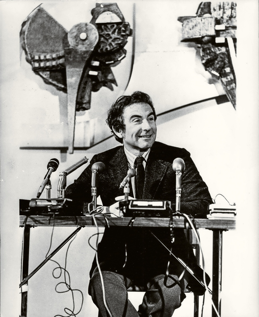 Archival image of Leon Cooper sitting behind a press table.