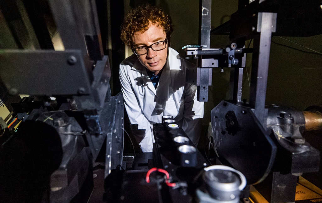 A student with glasses behind scientific equipment