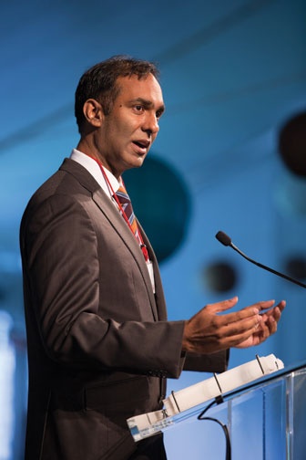 Photograph of Jaykumar A. Menon, class of '90, standing at a podium.