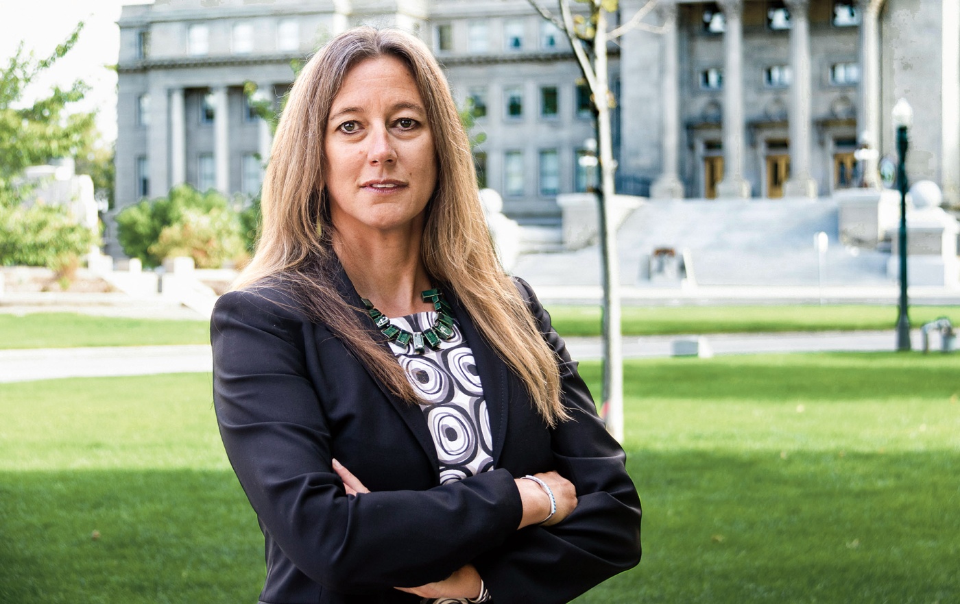 Julie Lyons standing with her arms crossed in front of a state building.