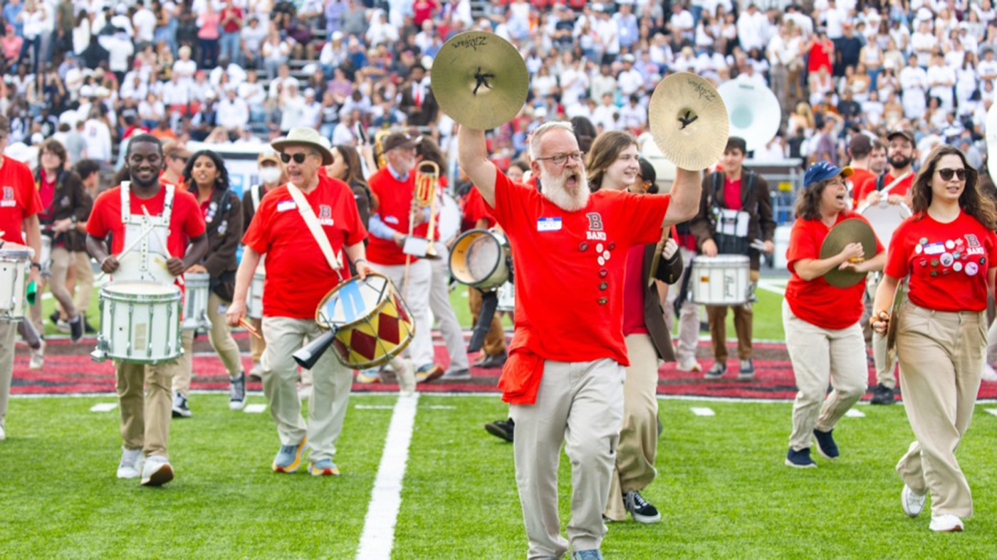 Brown Band alumni perform on the field at halftime of a football game against Harvard.