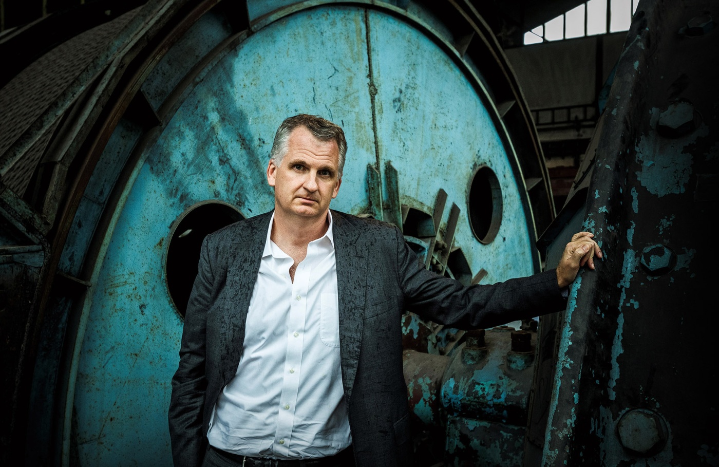 Image of Timothy Snyder standing with an old defunct factory wheel behind him.