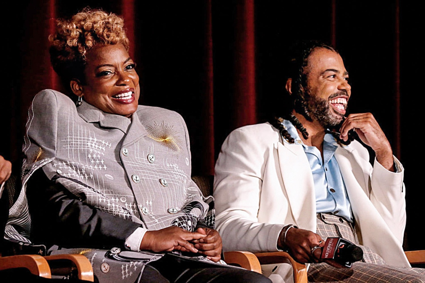 Image of Aunjanue Ellis and Daveed Diggs sitting on a stage smiling.