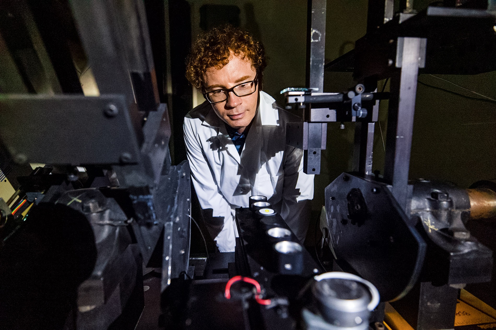 A student with glasses behind scientific equipment