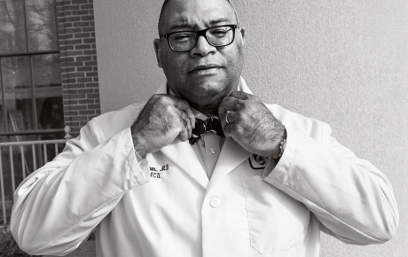 Archival black and white image of Galen Henderson tying a bowtie.