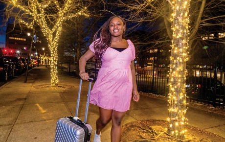 Image of Ayoola Fadahunsi pulling luggage down a night street.