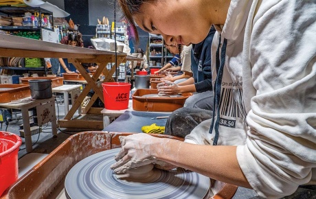 Image of a student using a pottery wheel in a studio